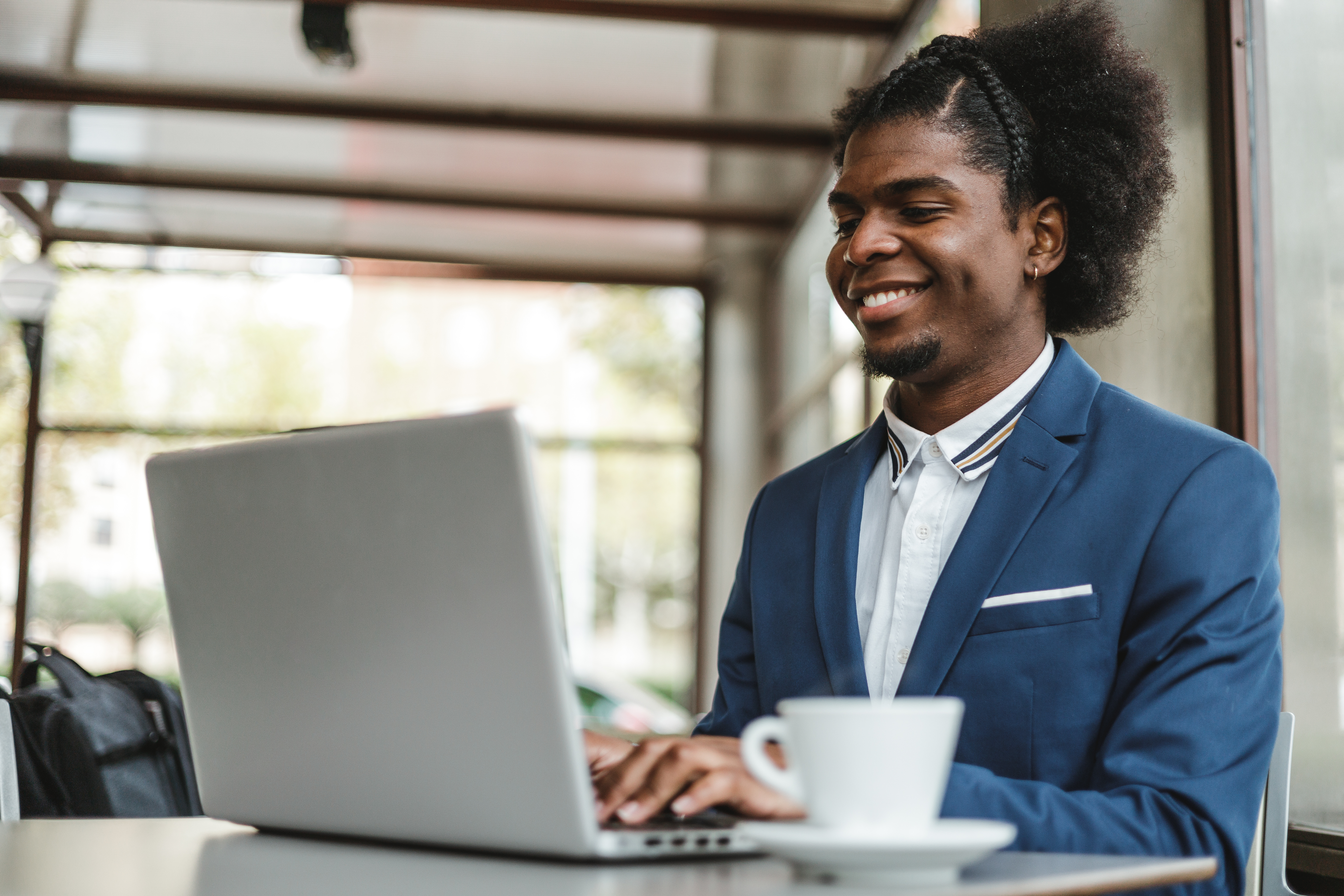 stylish african american businessman using laptop in cafe