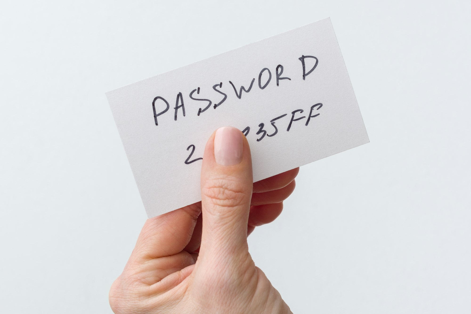 Woman's hand holds a password on paper, that covers the password with finger