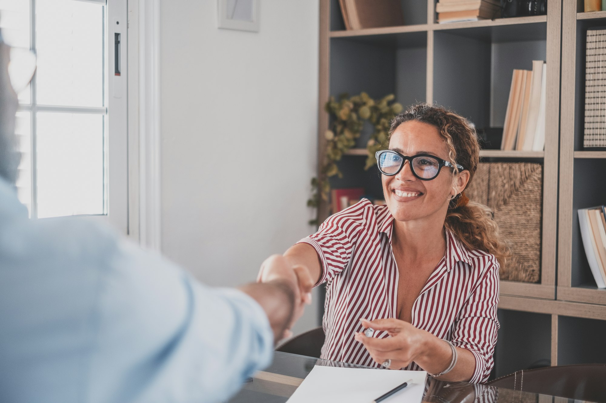 Smiling caucasian female hr manager handshake hire male candidate at job interview