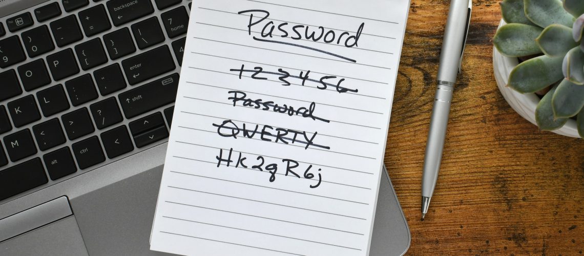Password list on notebook laying on keyboard of laptop computer on desk. Security strong password