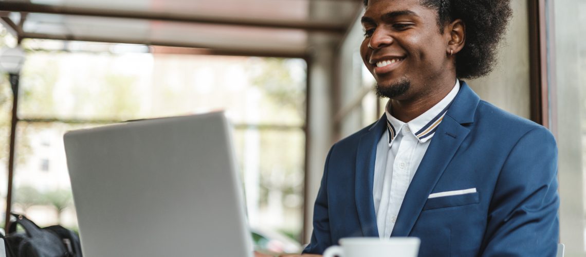 stylish african american businessman using laptop in cafe