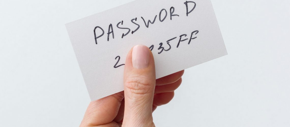 Woman's hand holds a password on paper, that covers the password with finger